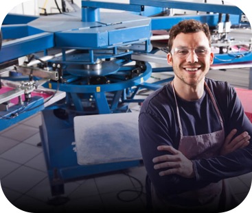 a man wearing safety glasses, standing in front of industrial mixing equipment